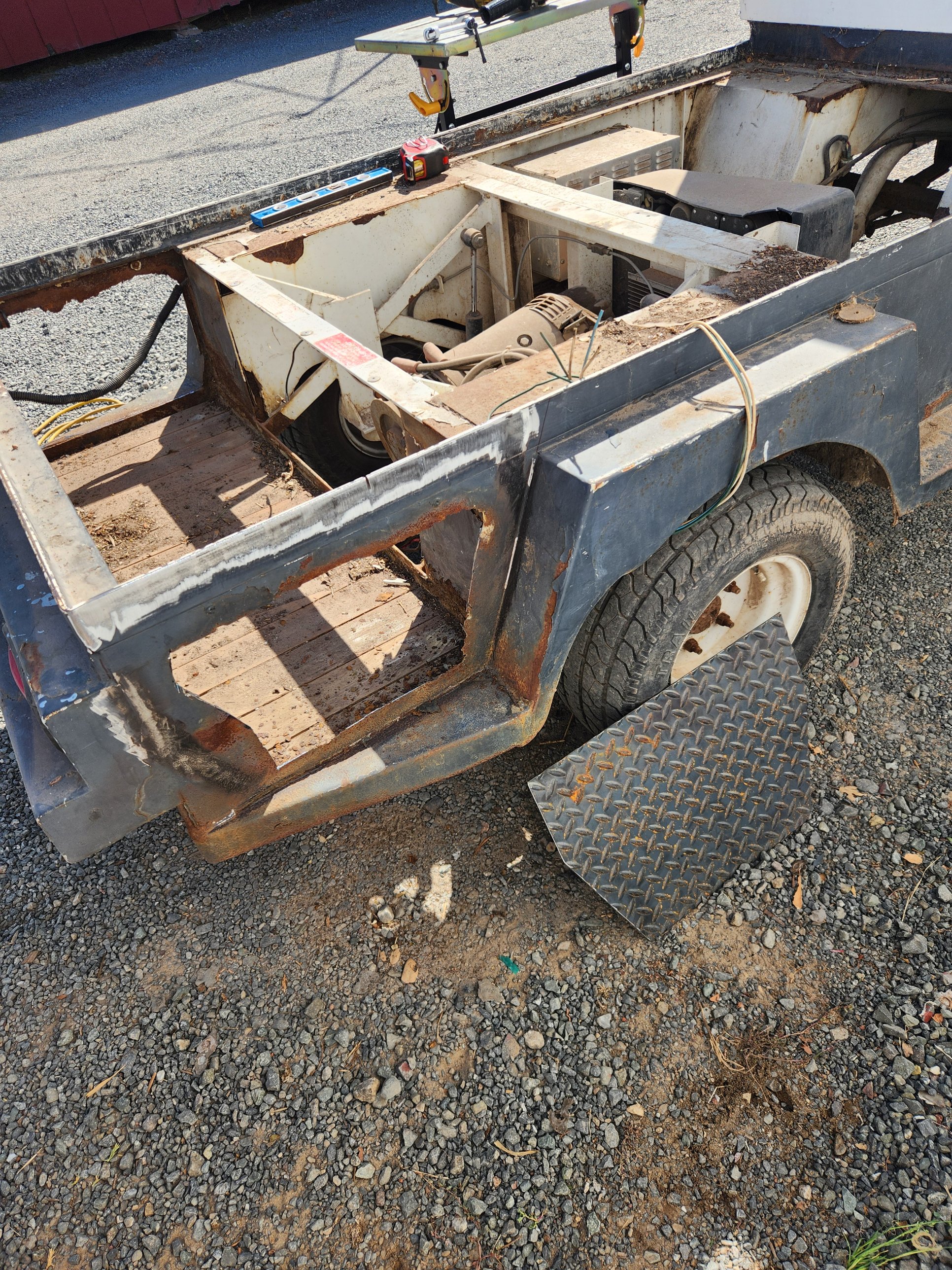 Overview of a golf cart battery compartment with rotted steel cut out, diamond-plate panel set aside, in Petaluma