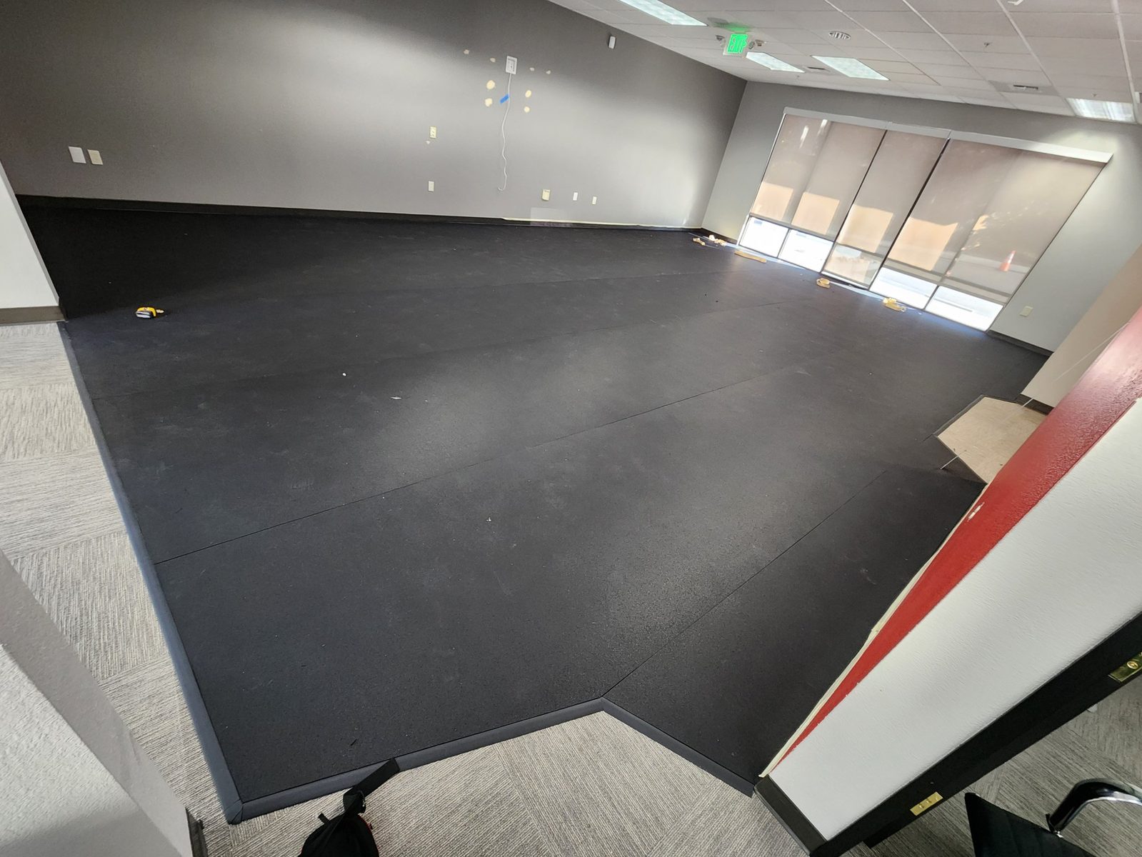 Edge ramp transition strip taped flush where rubber flooring meets carpet