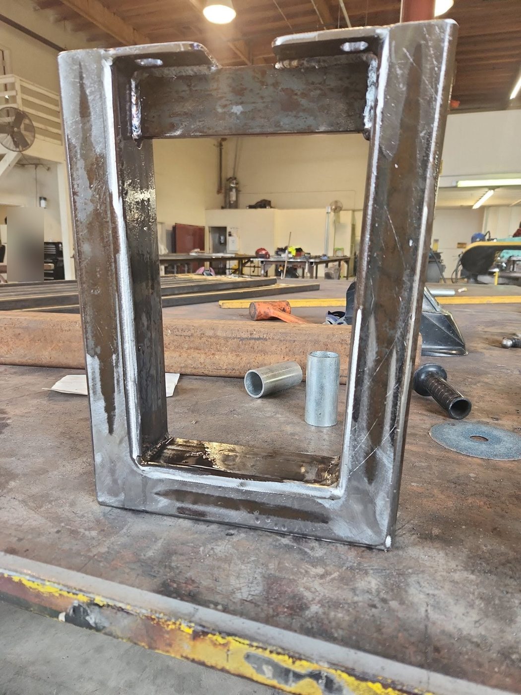 Welded steel bench leg frame with mounting plates on the table