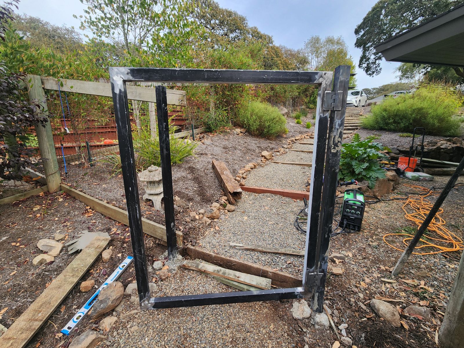Close-up of a welded steel hinge on a custom gate frame