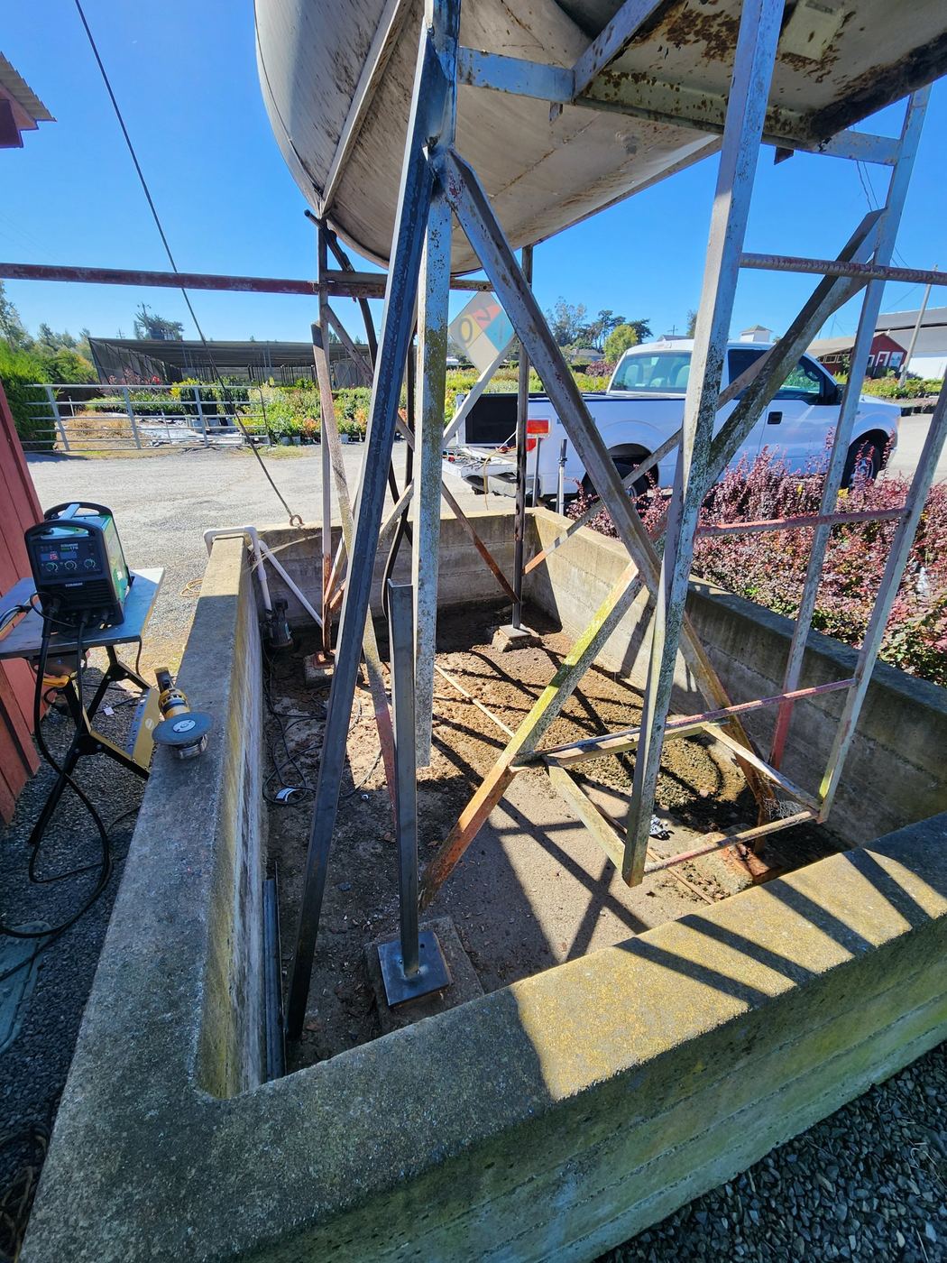 Two corner posts repaired with new welded base plates, welding equipment staged nearby