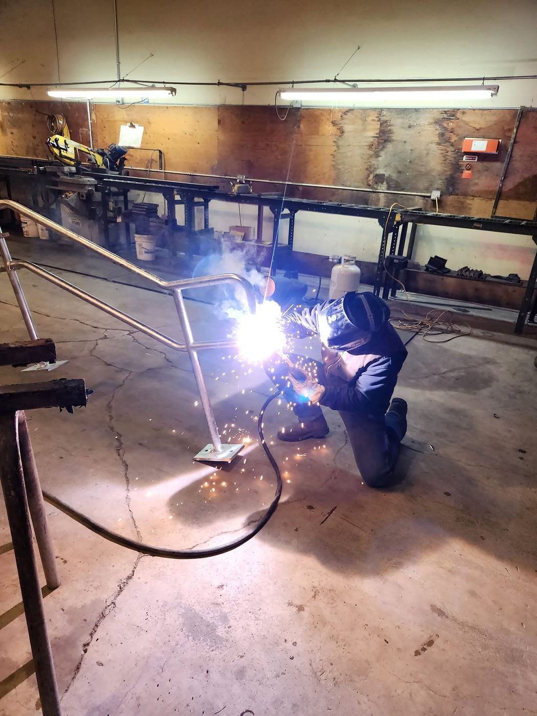 Welding a stair handrail into its base plate in the shop
